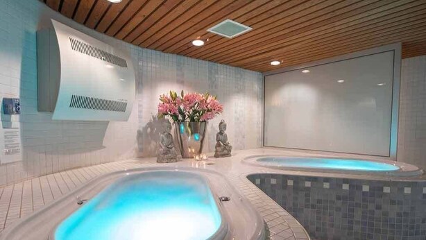 A spa area with two hot tubs, a wooden ceiling, and a wall-mounted air conditioning unit.