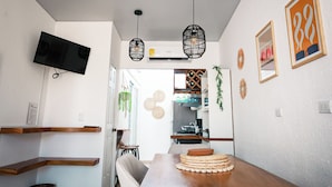 Una cocina moderna con una mesa de comedor de madera, plantas colgantes y un televisor montado.