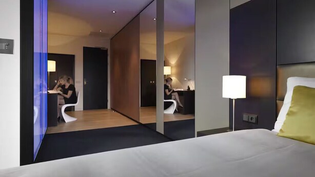 Habitación de hotel moderna con una cama grande, un escritorio y un espejo que refleja la habitación.