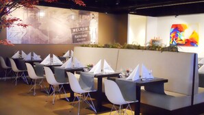 Un restaurante moderno con asientos tipo cabina y una pantalla de proyección mostrando un mensaje de bienvenida.