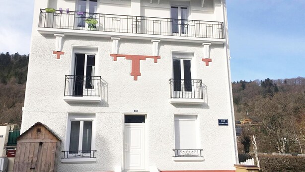 A multi-story building with balconies, windows, and a door.