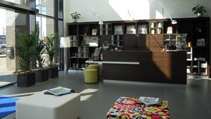 Un área de recepción moderna con mostrador, asientos y una estantería con diversos objetos.