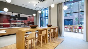 Una cocina moderna con una isla de madera, taburetes de bar y ventanas amplias con vistas a la ciudad.