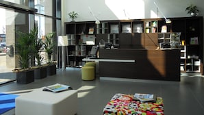 Un área de recepción moderna con mostrador, asientos y una estantería con diversos objetos.