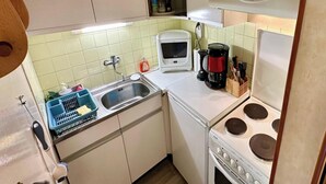 Una cucina compatta con piano cottura, lavello e forno a microonde.