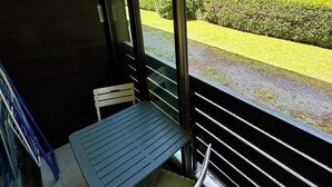Un balcone con tavolo e sedia, con vista su un giardino curato e un recinto.