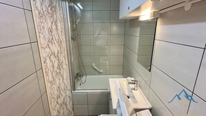 Un bagno con doccia vetrata, lavandino bianco e specchio.