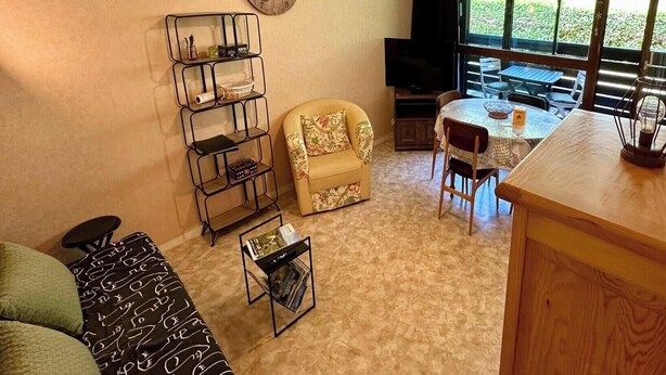 Un accogliente soggiorno con divano, tavolino, libreria, televisore e zona pranzo con tavolo e sedie.
