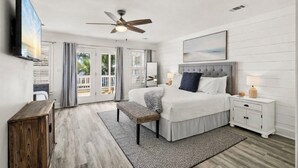 Ein Schlafzimmer mit Bett, Nachttischen, Deckenventilator, Fernseher und Blick ins Freie.