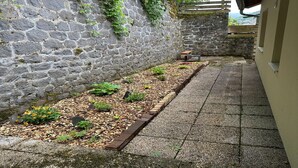 A stone wall with a brick planter bed and a tiled pathway. - Spacious Family Stayin Mont-Dore (Mont-Dore)