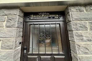 A stone building entrance with a dark wooden door, a metal gate, and a sign above the door that reads "Villa Janchrisma." - Spacious Family Stayin Mont-Dore (Mont-Dore)