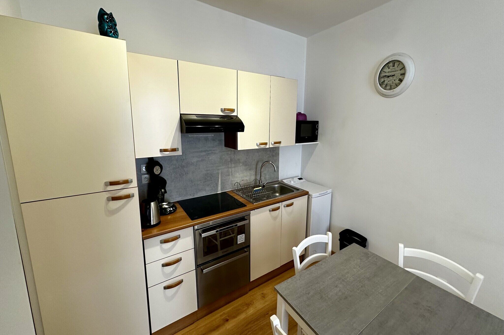 A compact kitchen with white cabinets, a black stove, and a microwave.