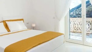 A bedroom with a bed, a nightstand, and a view of a balcony. - Villa Domi by My Villa Collection (Amalfi)