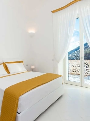 A bedroom with a bed, a nightstand, and a view of a balcony. - Villa Domi by My Villa Collection (Amalfi)