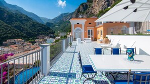 A terrace with a tiled floor, outdoor seating, and a view of a mountainous landscape. - Villa Domi by My Villa Collection (Amalfi)