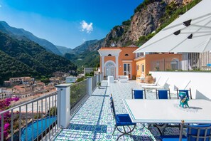 A terrace with a tiled floor, outdoor seating, and a view of a mountainous landscape. - Villa Domi by My Villa Collection (Amalfi)