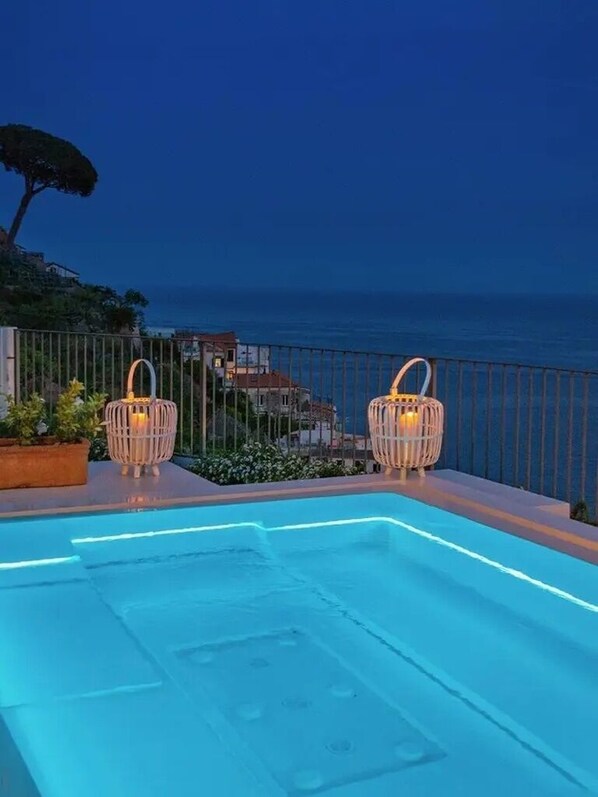 A swimming pool with two wicker lanterns and a view of the sea at dusk. - Villa Domi by My Villa Collection (Amalfi)