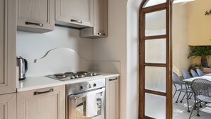 A kitchen with wooden cabinets, a stainless steel stove, and a view of an outdoor patio with chairs and a table. - Villa Deus by My Villa Collection (Nocelle)