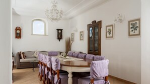 A dining area with a round table, purple chairs, a chandelier, and wall-mounted clocks. - Villa Deus by My Villa Collection (Nocelle)