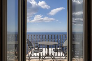 A balcony with a table and chairs, overlooking the sea. - Villa Deus by My Villa Collection (Nocelle)