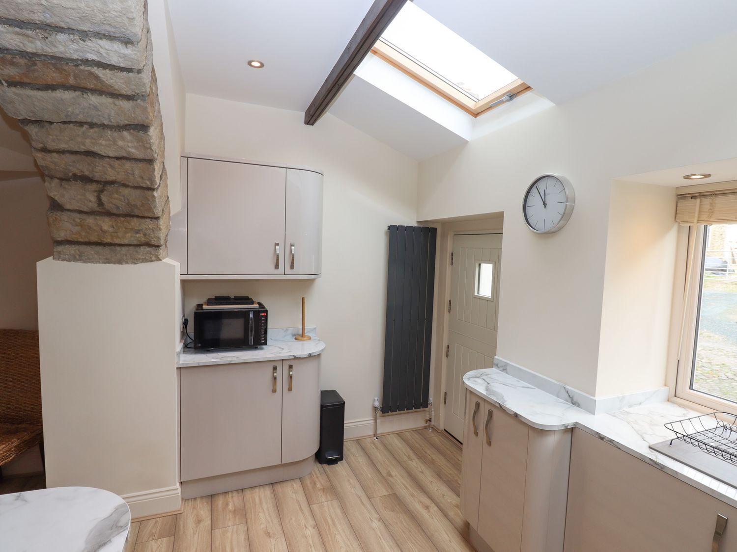 A compact kitchen with a skylight, a clock, and a view of the outside.