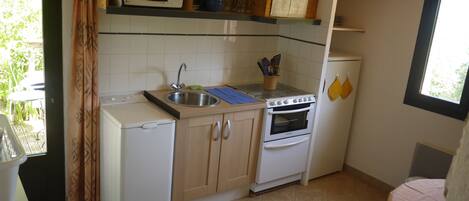 Una cocina compacta equipada con microondas, fregadero, horno y un refrigerador pequeño.