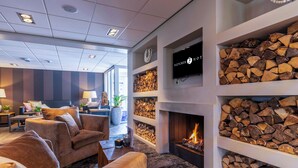 Un salon moderne doté de canapés, d’une cheminée et d’un téléviseur fixé au mur.
