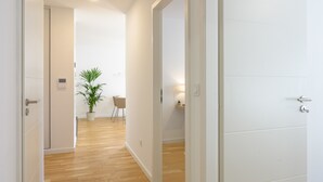 A hallway with wooden flooring, white walls, and a potted plant. - Colmar Chic – Modern Old Town Apartment with Wi-Fi, Garage, Elevator for 2–6 Guests (Colmar)