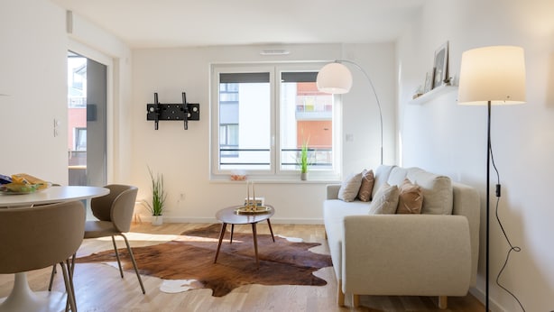 A modern living room with a sofa, a coffee table, a dining table with chairs, a cowhide rug, and a large window with a view of buildings. - Colmar Chic – Modern Old Town Apartment with Wi-Fi, Garage, Elevator for 2–6 Guests (Colmar)