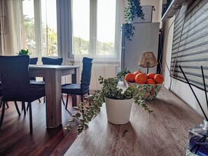 Comedor con mesa de madera, sillas azules, un bol de naranjas y una planta en maceta.