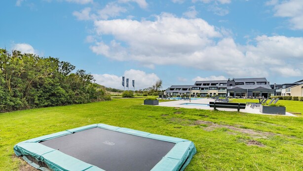 Un trampolín en un área con césped, con un edificio al fondo.