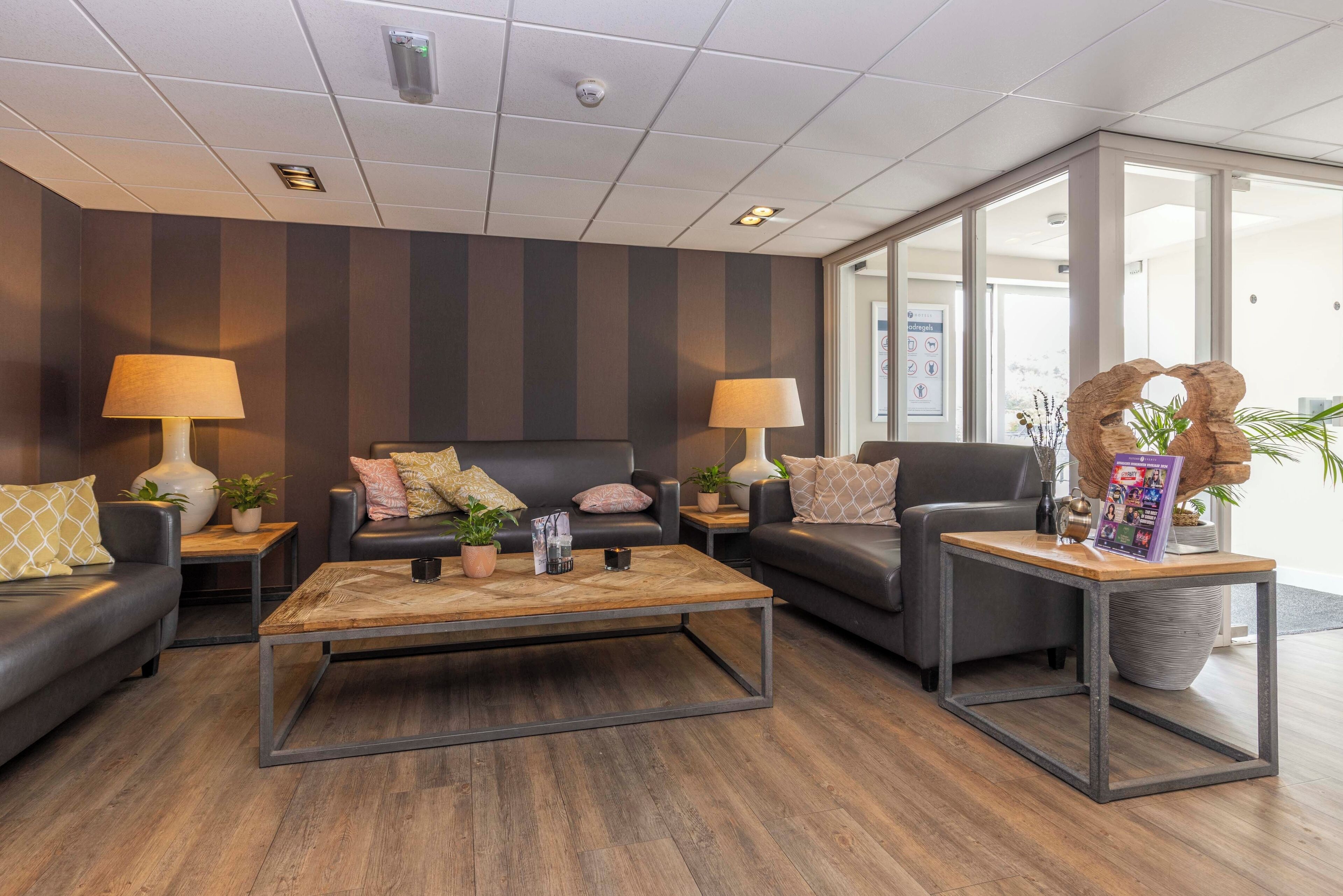 Een moderne woonkamer met twee banken, een salontafel en lampen. Er staan potplanten en een decoratief object op de salontafel.