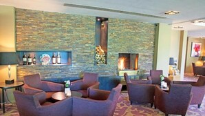 A lobby with a stone wall, a fireplace, and seating areas. - Room with Balcony! Indoor Pool, Close to National Park De Sallandse Heuvelrug! (Rijssen)