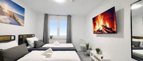 A modern hotel room with two beds, a large window with curtains, a fireplace painting, and a mirror on the wall.