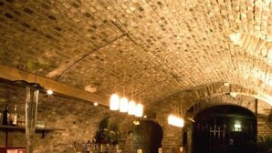 Un bar con techo de ladrillo y taburetes rojos acolchados.