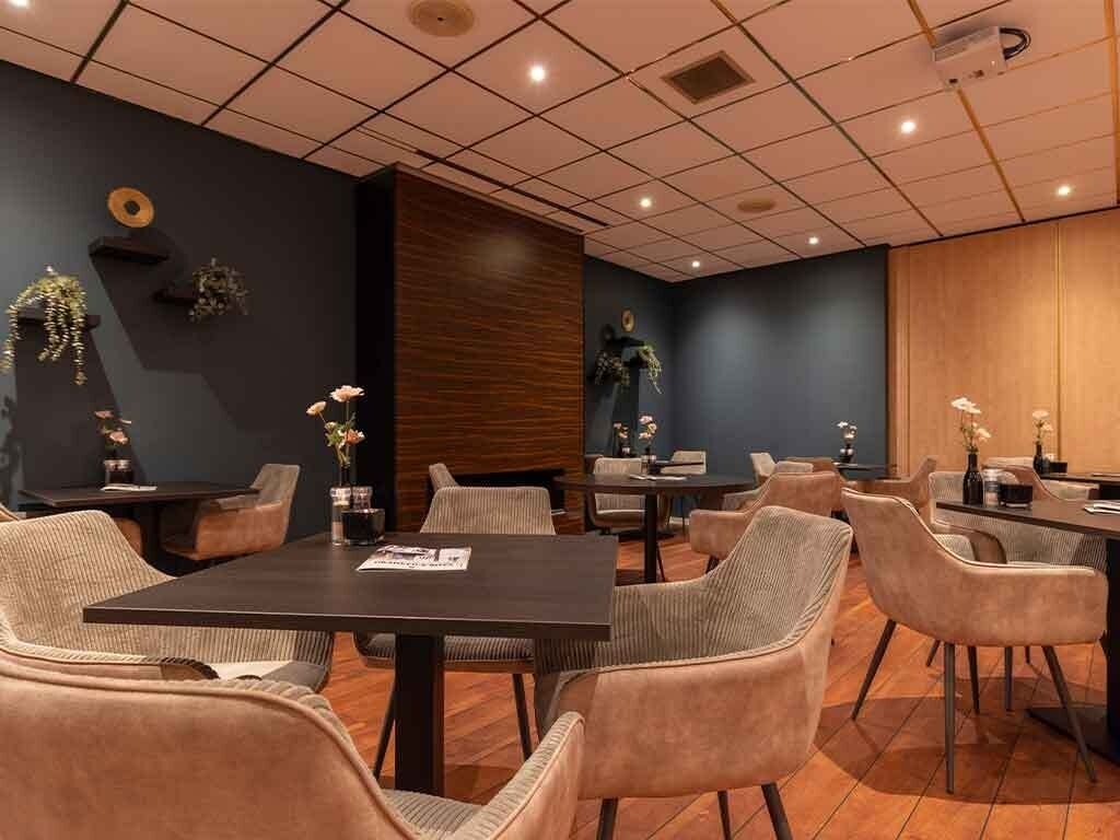 Une salle de conférence avec un mur lambrissé en bois foncé, plusieurs tables et des chaises.
