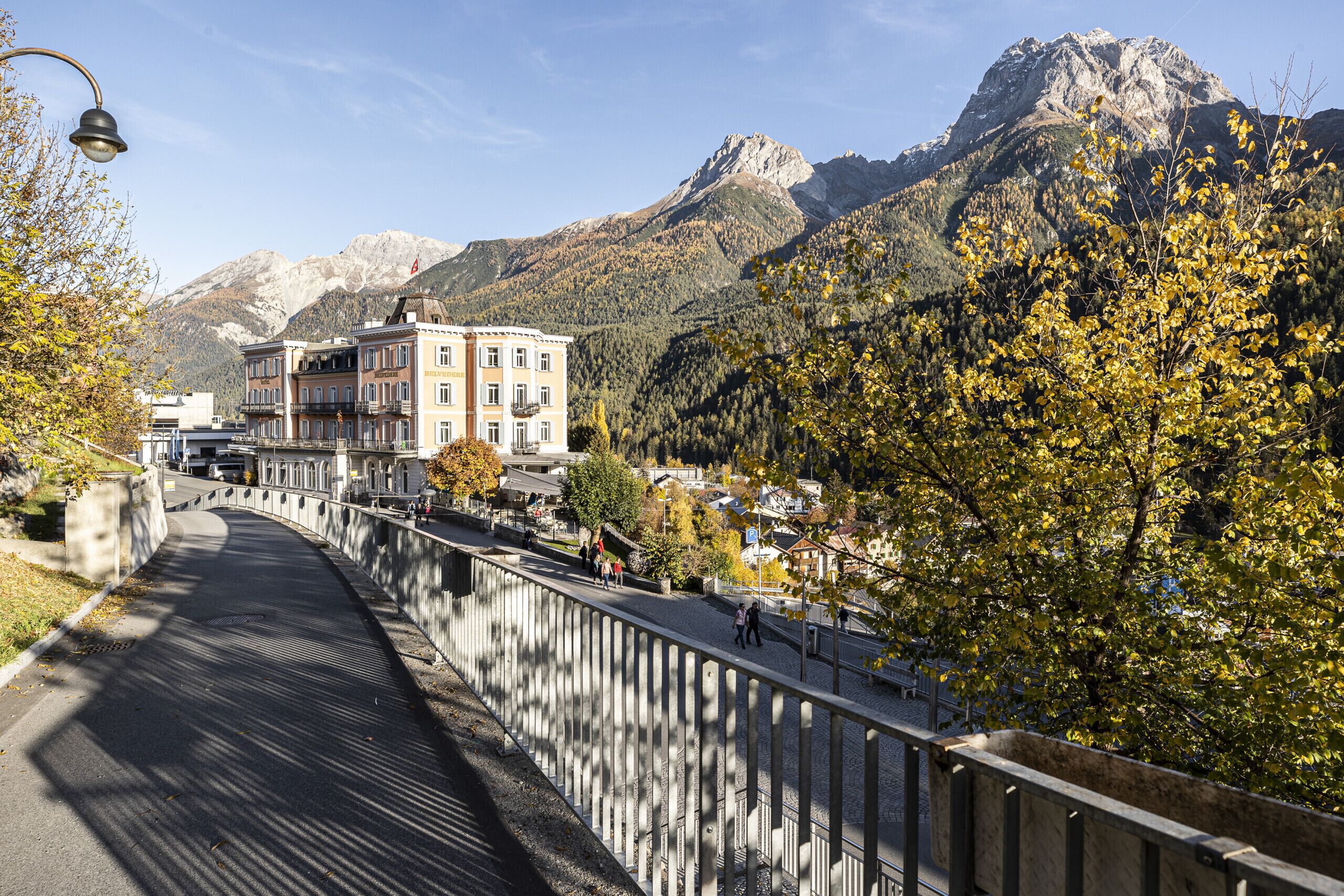 Uma ponte com um edifício à esquerda e montanhas ao fundo.