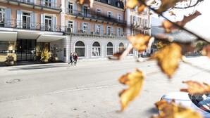 Un hotel a più piani con un cortile centrale, ampie finestre e un balcone ai piani superiori.