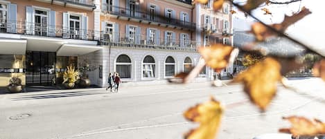 Un hotel a più piani con un cortile centrale, ampie finestre e un balcone ai piani superiori.