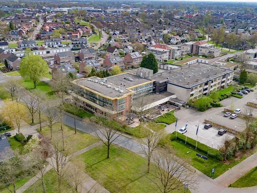 Vista aérea de una zona residencial con un edificio moderno de techo plano y grandes ventanales.