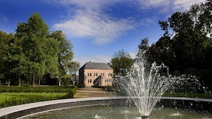 Ein Brunnen in einem kreisförmigen Wasserspiel mit einem Gebäude im Hintergrund.