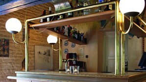 Een bar met een houten toonbank, barkrukken en een spiegel erboven.