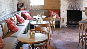 Een gezellig restaurant met stenen muren, houten meubels en een open haard.