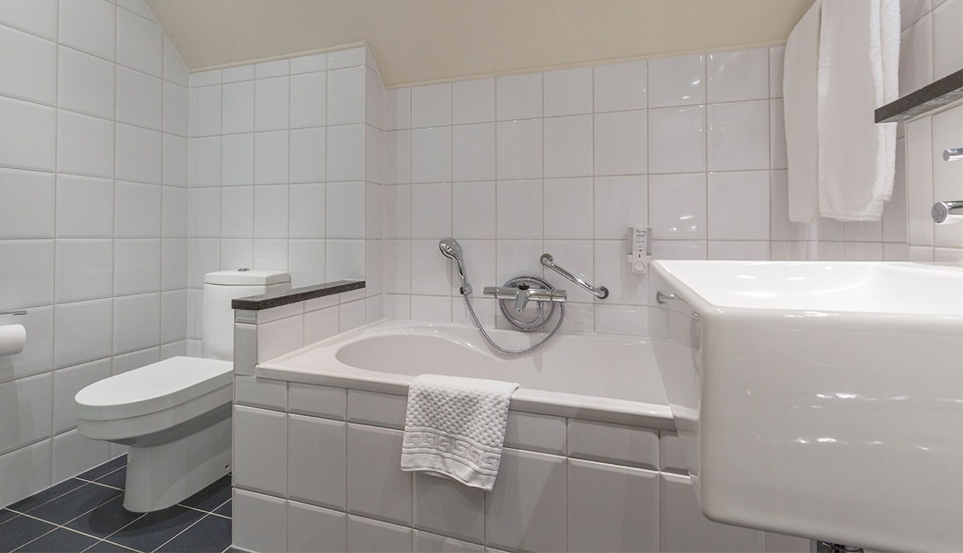 Et moderne badeværelse med toilet, badekar og vask.