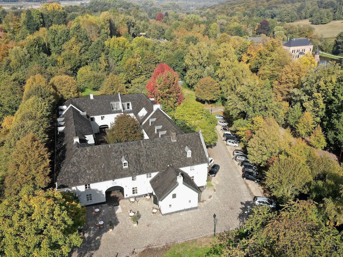 A white building with a grey roof surrounded by trees.