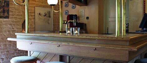A bar area with a wooden counter, stools, and a mirror above the bar.