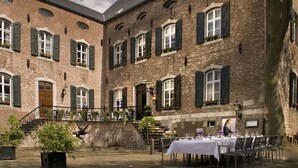 Une cour intérieure aménagée avec un espace repas pour les repas, entourée d’immeubles en briques dotés de nombreuses fenêtres et de volets.