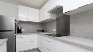A modern kitchen with white cabinets, a stainless steel refrigerator, a coffee maker, and a sink. - Renovated Apartment with Private Garden, 150m from Saint-Colomban Beach (Carnac)