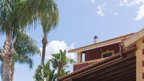 Un edificio con un portico coperto, circondato da palme e altra vegetazione tropicale.