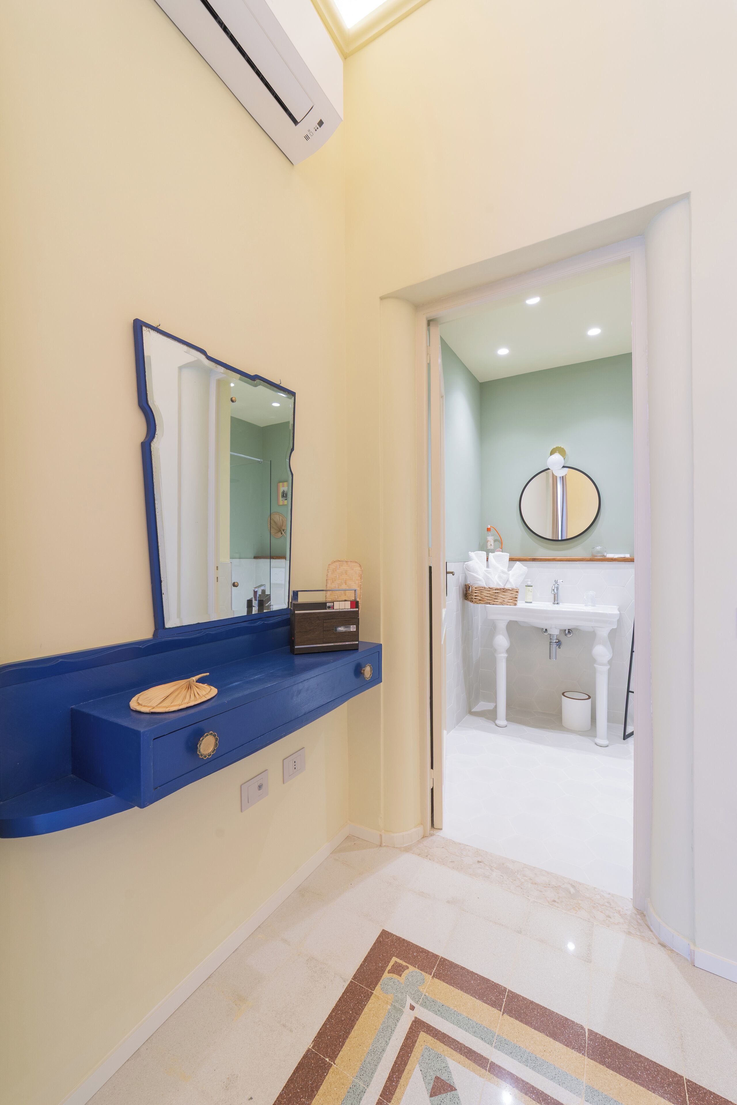 Un bagno con un mobile blu, un lavandino bianco e uno specchio.